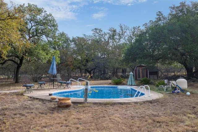 a view of a wooden house with a yard and large trees