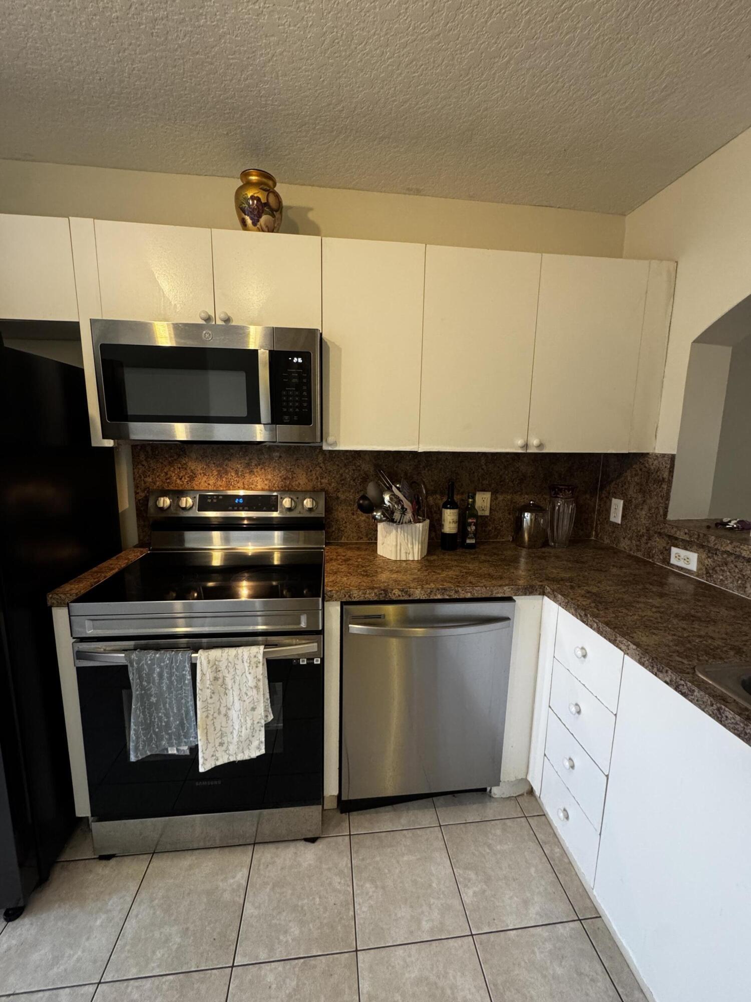 3810 North Jog Road, Unit 105 Royal Palm Beach, FL 33411 - Photo 16 of 26 a kitchen with stainless steel appliances granite countertop a stove a sink and a microwave
