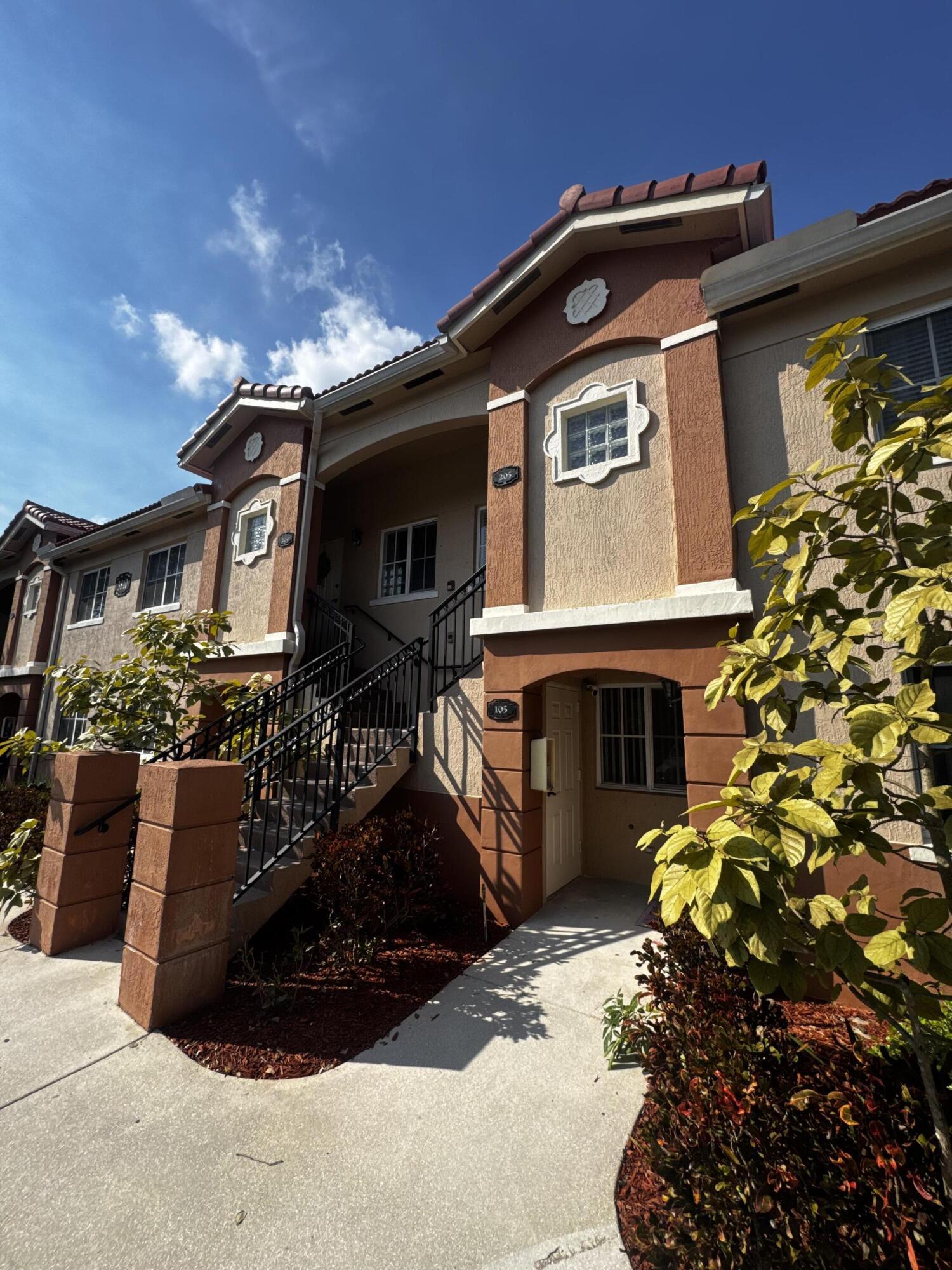 3810 North Jog Road, Unit 105 Royal Palm Beach, FL 33411 - Photo 2 of 26 a front view of a house with a yard