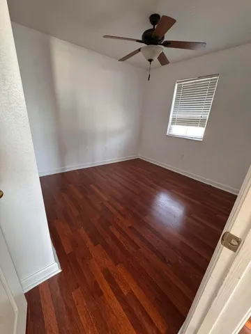 a view of an empty room with a window and a ceiling fan