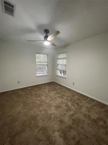 an empty room with windows and ceiling fan