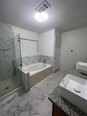a spacious bathroom with a granite countertop sink a mirror and a bathtub