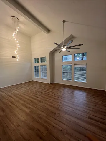 a view of a room with wooden floor ceiling fan and window