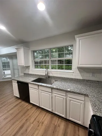 a kitchen with granite countertop wooden cabinets a sink and dishwasher with wooden floor
