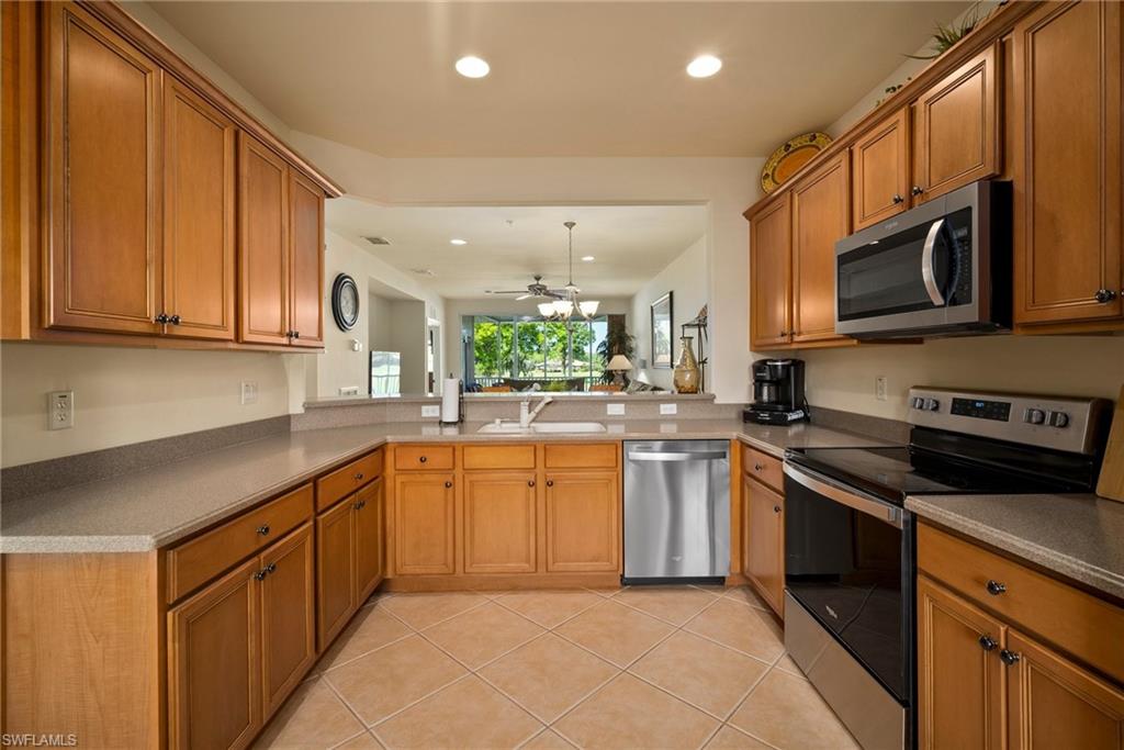9113 Michael Circle, Unit 4 Naples, FL 34113 - Photo 7 of 23 Kitchen featuring appliances with stainless steel finishes, kitchen peninsula, sink, light tile flooring, and ceiling fan