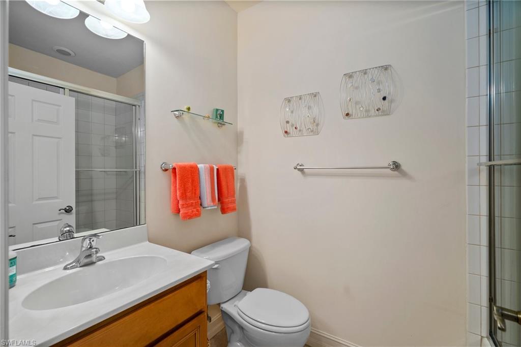 9113 Michael Circle, Unit 4 Naples, FL 34113 - Photo 9 of 23 Bathroom with a shower with shower door, toilet, and vanity