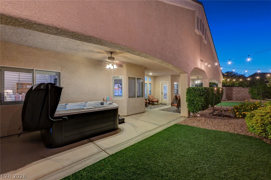 1604 Cattle Ranch Place Henderson, NV 89002 - Photo 86 of 99 Unwind in the private spa on the covered patio, extending to a well-maintained yard under string lights.