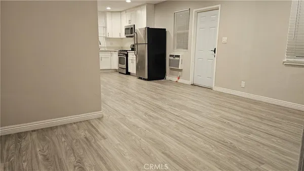 a view of a kitchen with refrigerator and wooden floor