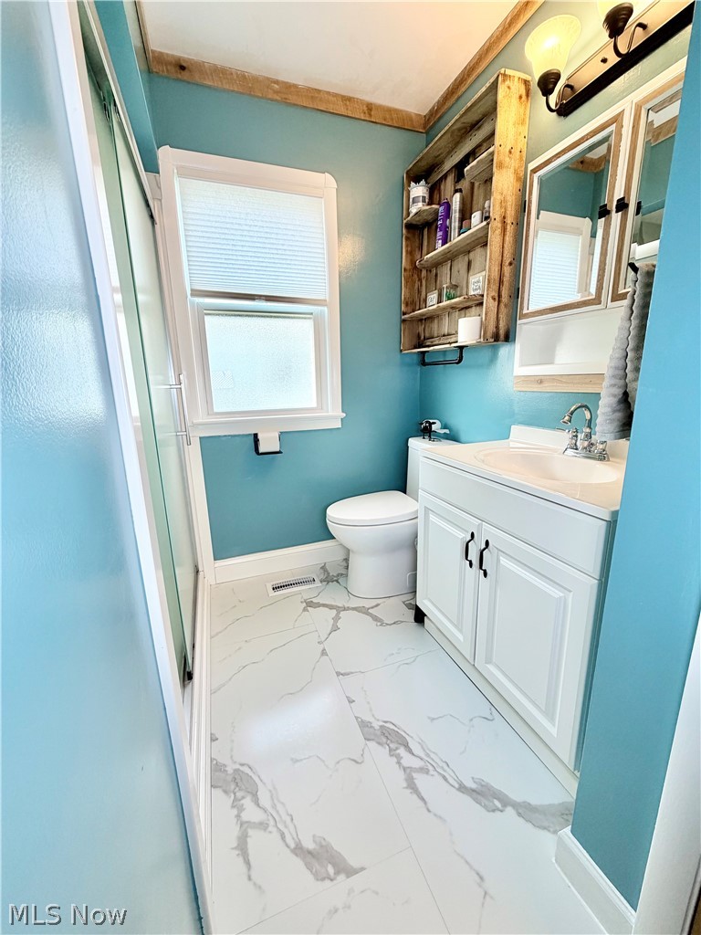 32125 Densmore Road Willowick, OH 44095 - Photo 11 of 23 Bathroom featuring a white vanity with double-door cabinetry, a white toilet, and a window with privacy blinds