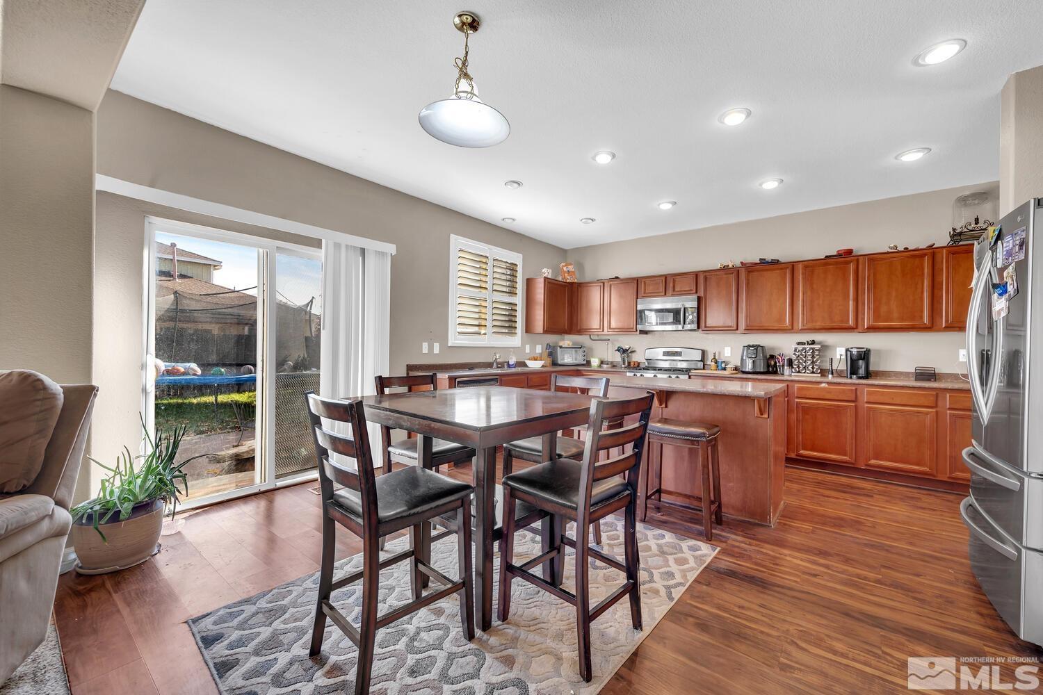 8970 Sorcha Street Reno, NV 89506 - Photo 7 of 38 a kitchen with stainless steel appliances granite countertop wooden floor dining table and chairs