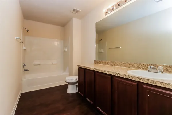a bathroom with a granite countertop sink toilet a large mirror a bathtub and shower