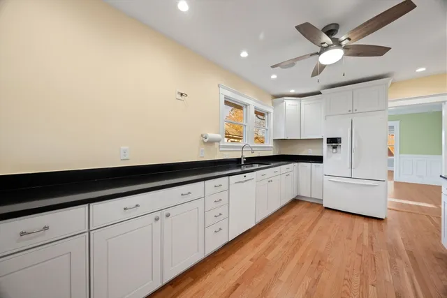 a large white kitchen with stainless steel appliances granite countertop a sink and cabinets