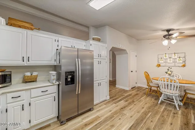 a kitchen with stainless steel appliances a refrigerator a stove a dining table and chairs with wooden floor