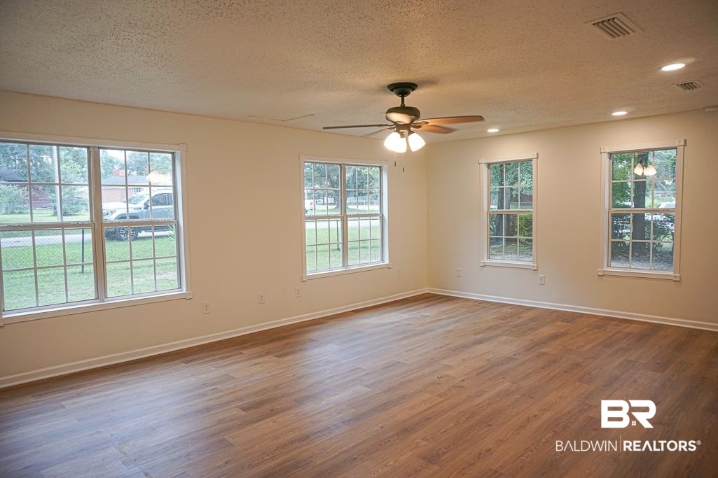 4734 Kirkwell Drive Mobile, AL 36619 - Photo 3 of 18 Unfurnished room with a textured ceiling, a healthy amount of sunlight, hardwood / wood-style floors, and ceiling fan