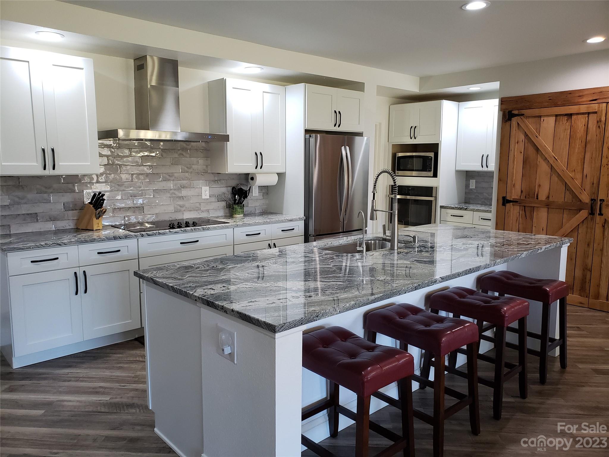 204 Mountain Spring Lane Canton, NC 28716 - Photo 4 of 18 a kitchen with stainless steel appliances kitchen island granite countertop a table chairs in it and wooden floors