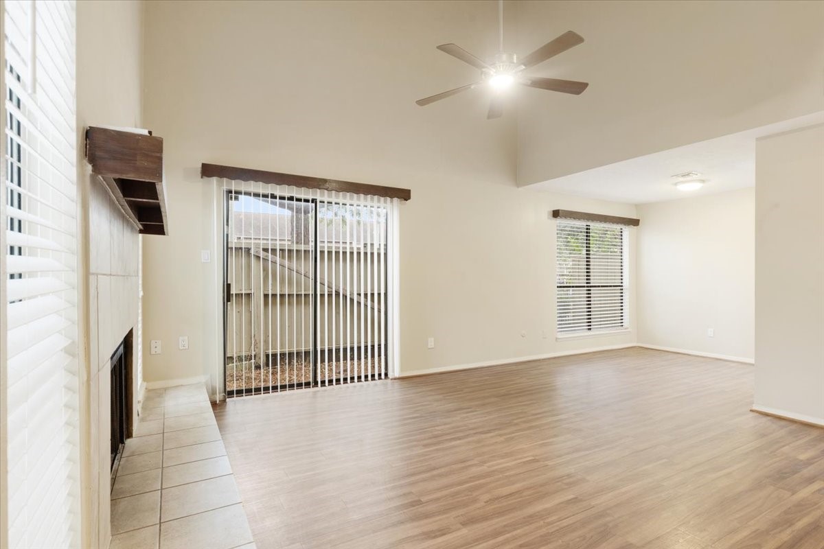 3502 Ocee Street, Unit 3502 Houston, TX 77063 - Photo 3 of 28 This spacious living area features hardwood floors, a cozy fireplace, and ample natural light through large windows and sliding glass doors leading to a fenced outdoor space. A ceiling fan adds modern comfort.