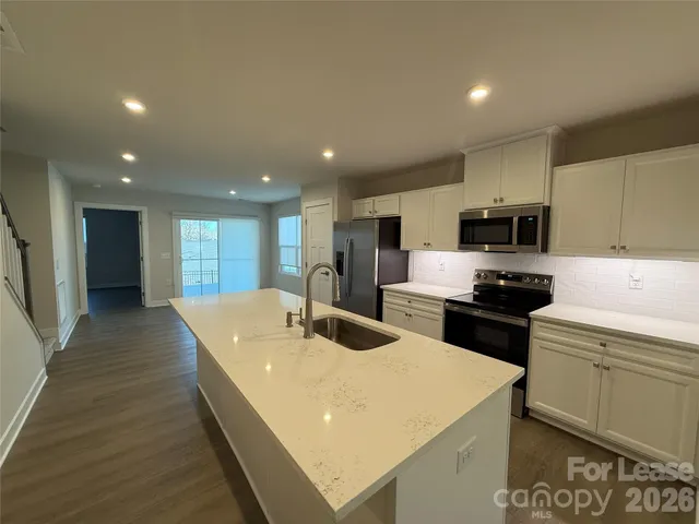 a kitchen with stainless steel appliances granite countertop a sink dishwasher stove top oven and refrigerator with wooden floor