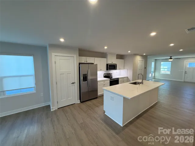 a large kitchen with a center island wooden floor and stainless steel appliances