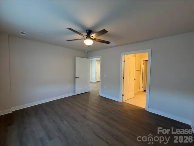 an empty room with wooden floor and a ceiling fan