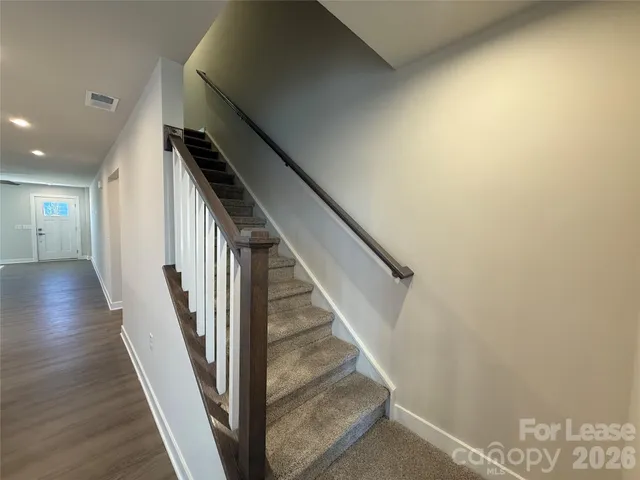a view of a hallway with wooden floor and staircase