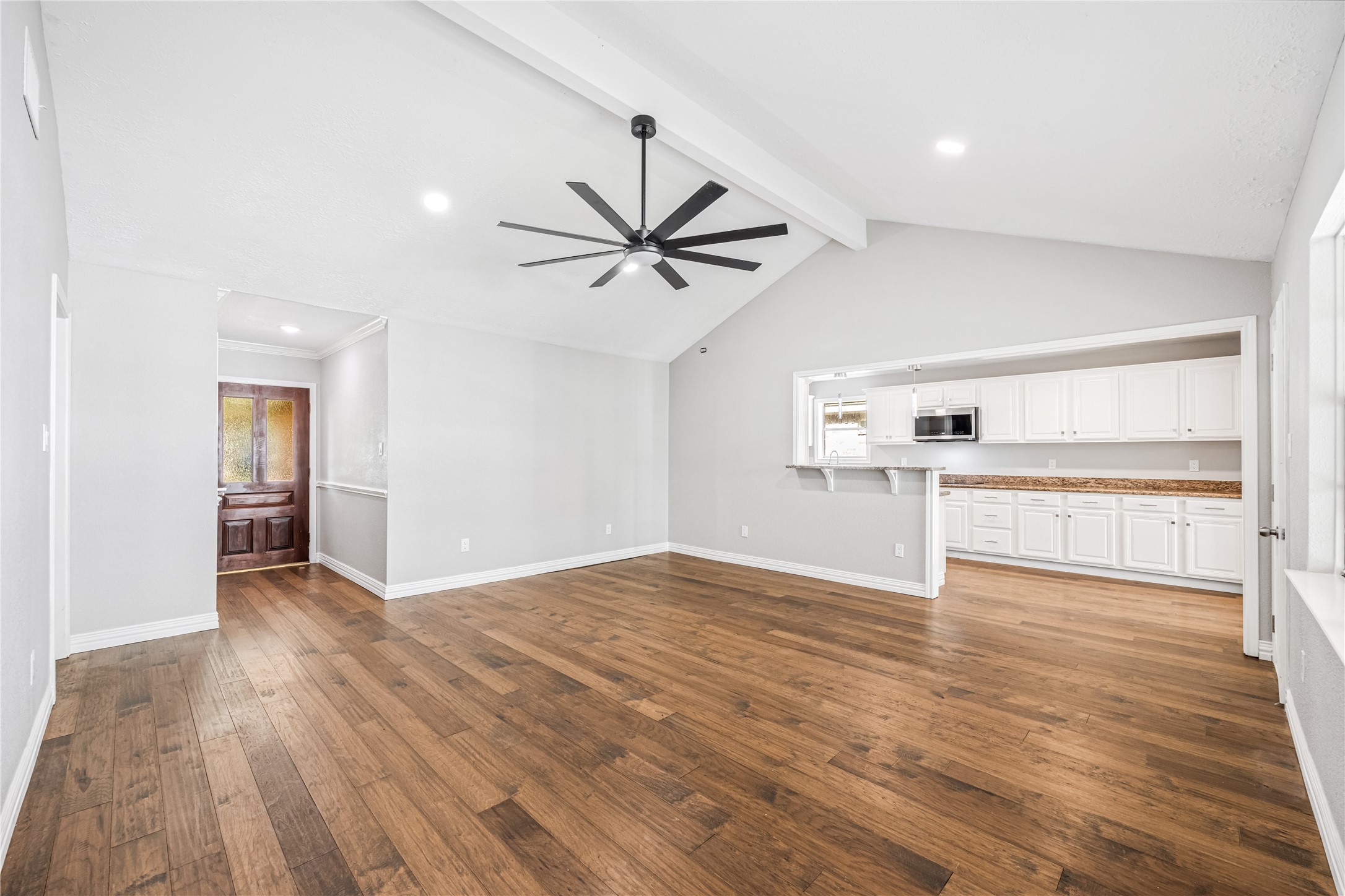9806 Tanager Lane Conroe, TX 77385 - Photo 7 of 28 a view of a kitchen with wooden floor and a ceiling fan