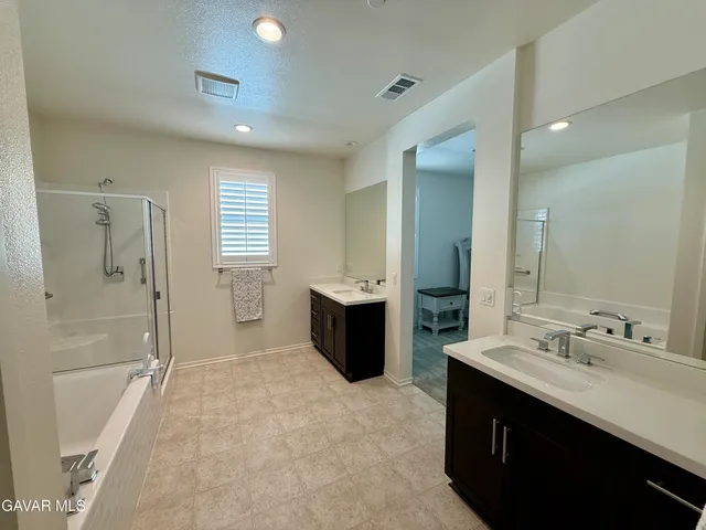 a bathroom with a double vanity sink a large mirror a shower and bathtub
