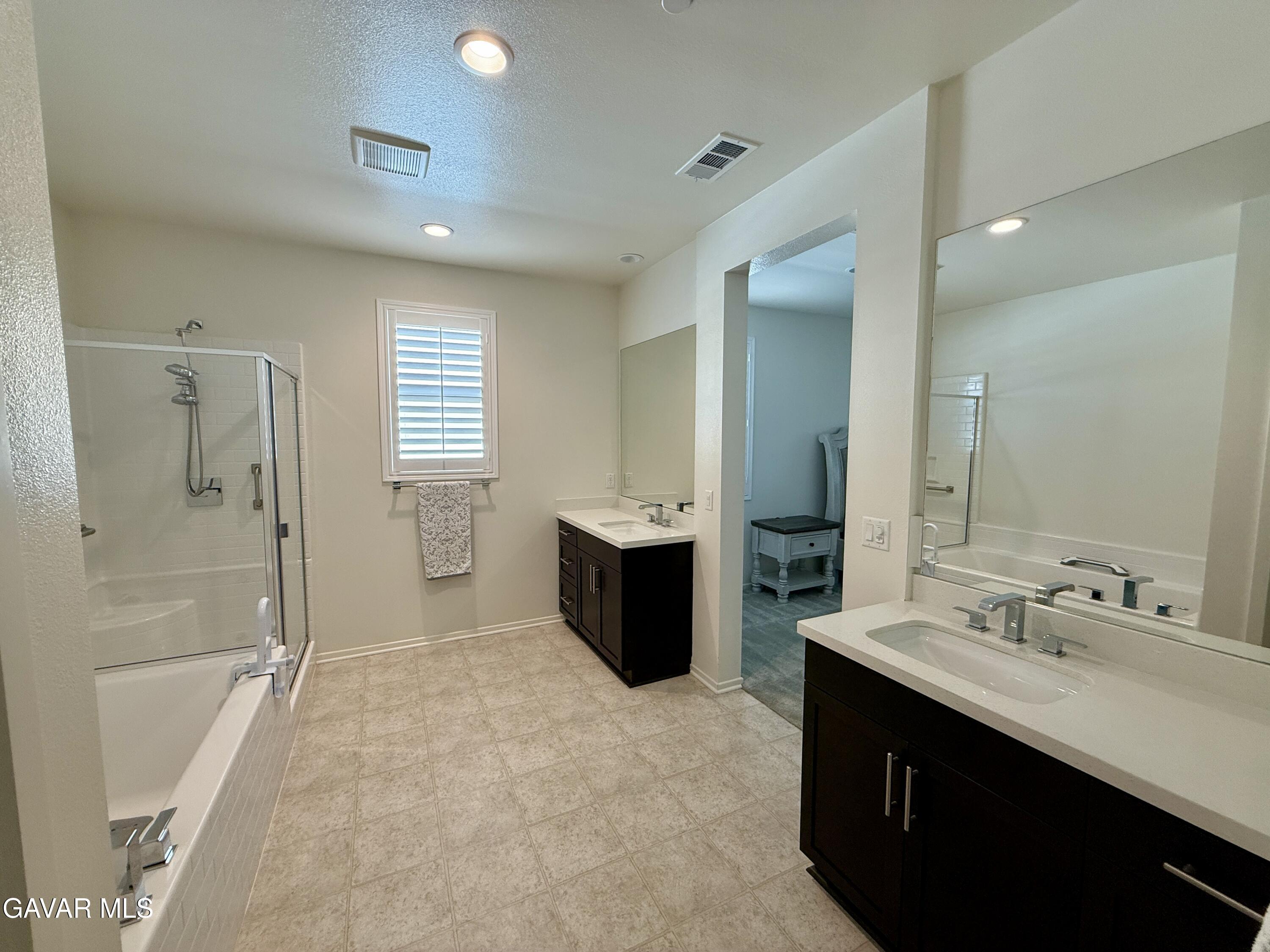 38902 Malva Rosa Drive Palmdale, CA 93551 - Photo 7 of 12 a bathroom with a double vanity sink a large mirror a shower and bathtub