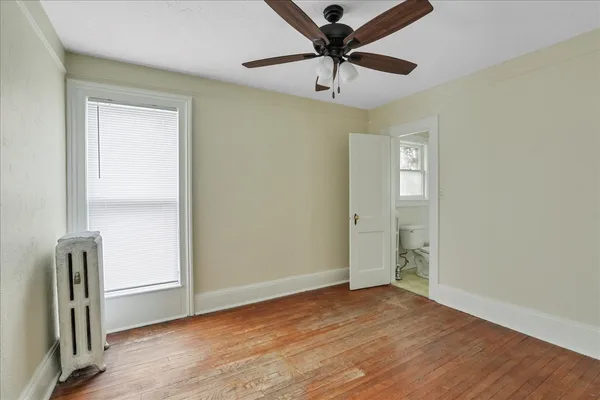 an empty room with wooden floor closet and windows