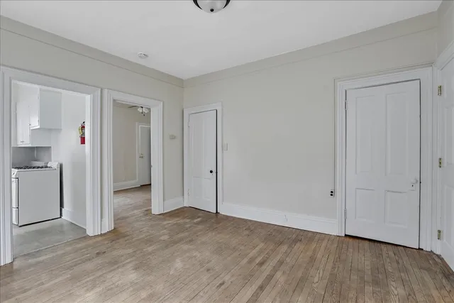 a view of an empty room with wooden floor and closet