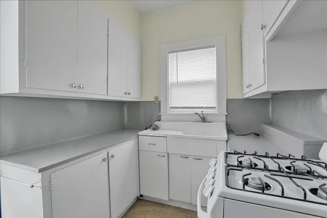a kitchen with white cabinets and sink