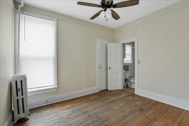 an empty room with wooden floor closet and windows