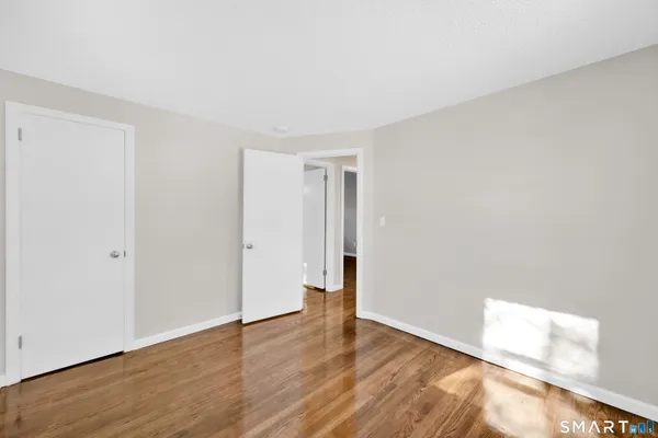 a view of an empty room with wooden floor and closet