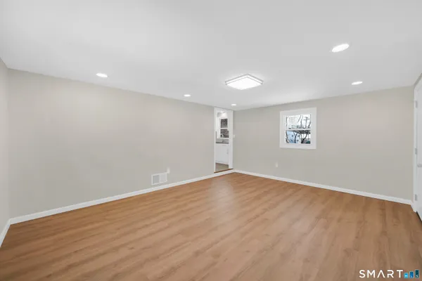 a view of an empty room with wooden floor and a window