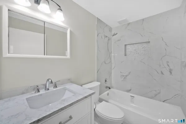a bathroom with a granite countertop sink toilet and shower