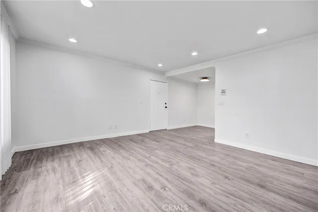 an empty room with wooden floor and natural light