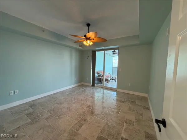 an empty room with a chandelier fan and windows