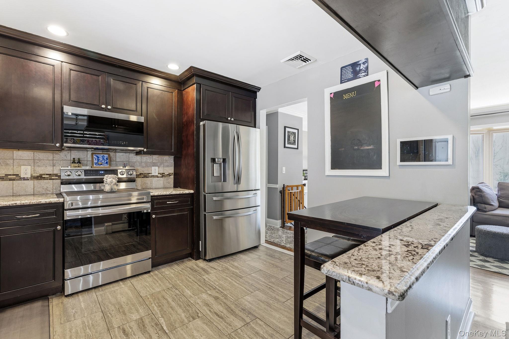 56 Tanager Road Mahopac, NY 10541 - Photo 10 of 30 a kitchen with stainless steel appliances kitchen island granite countertop a refrigerator a stove and a sink with wooden floor
