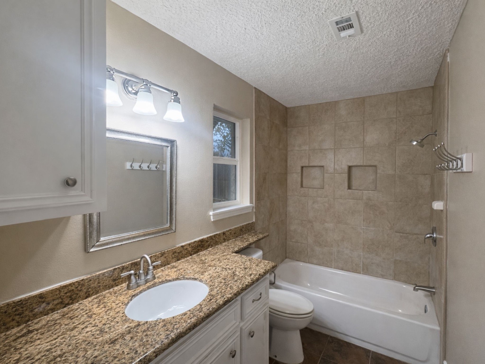 1318 Epsilon Street Pasadena, TX 77504 - Photo 11 of 15 a bathroom with a granite countertop sink a toilet a mirror a bathtub and shower