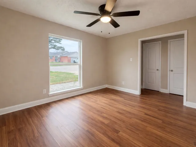 a view of empty room with wooden floor and fan