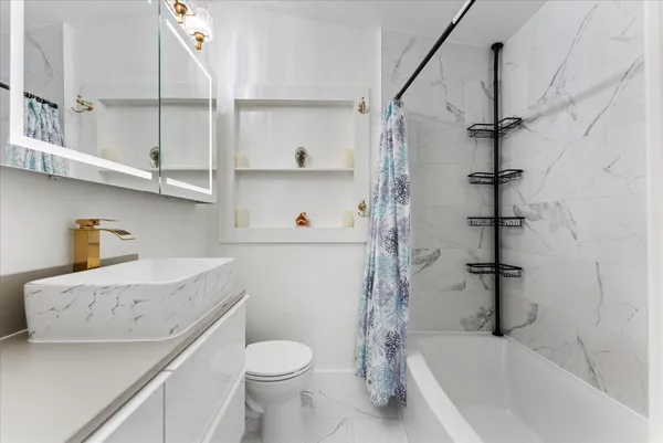 a bathroom with a granite countertop sink toilet and shower