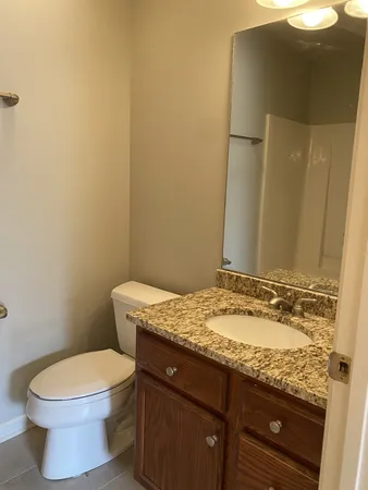 a bathroom with a granite countertop toilet and a sink