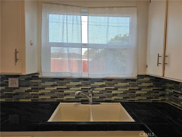 a view of a kitchen with kitchen island a counter space a sink and a window