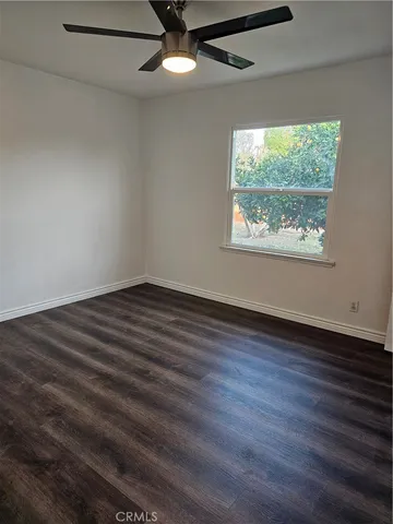 an empty room with wooden floor chandelier fan and windows