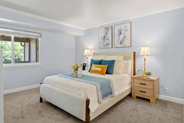a bedroom with a bed a painting on the wall and a window