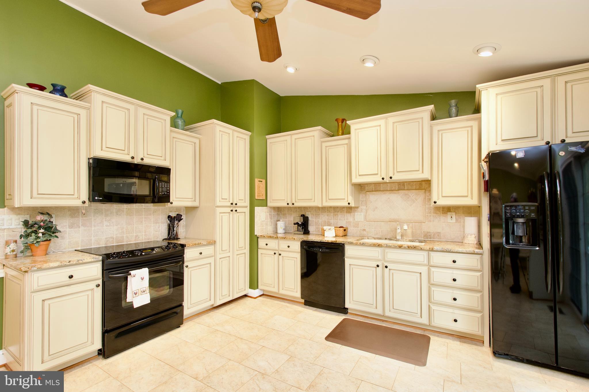 6690 Old Blacksmith Drive Burke, VA 22015 - Photo 15 of 46 a kitchen with stainless steel appliances kitchen island granite countertop a refrigerator a stove top oven a sink dishwasher and white cabinets with wooden floor