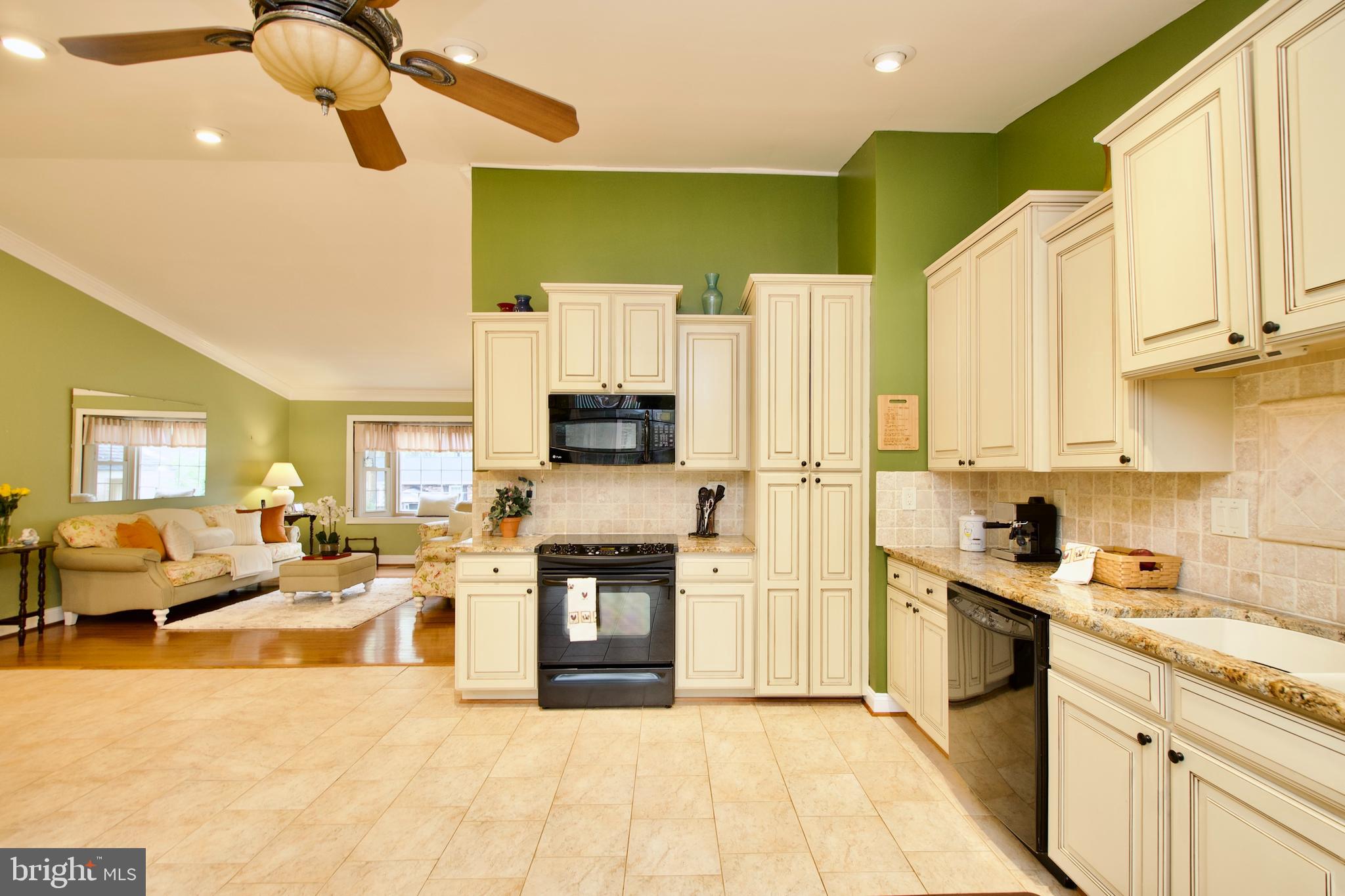 6690 Old Blacksmith Drive Burke, VA 22015 - Photo 16 of 46 a kitchen with stainless steel appliances granite countertop a sink a stove top oven a chimney cabinets and living room view