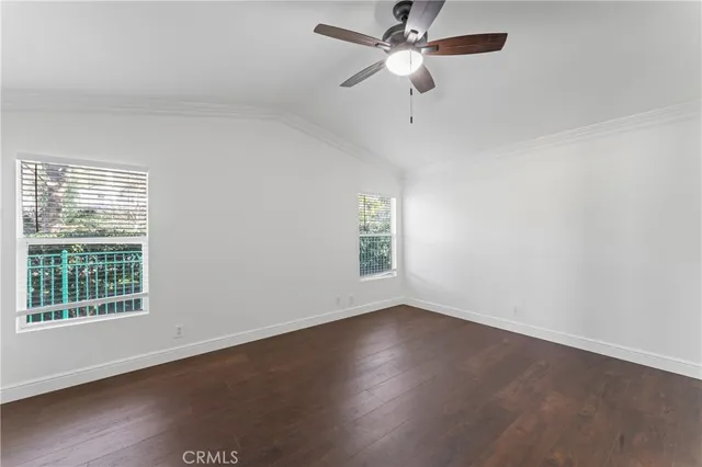 an empty room with wooden floor chandelier fan and windows