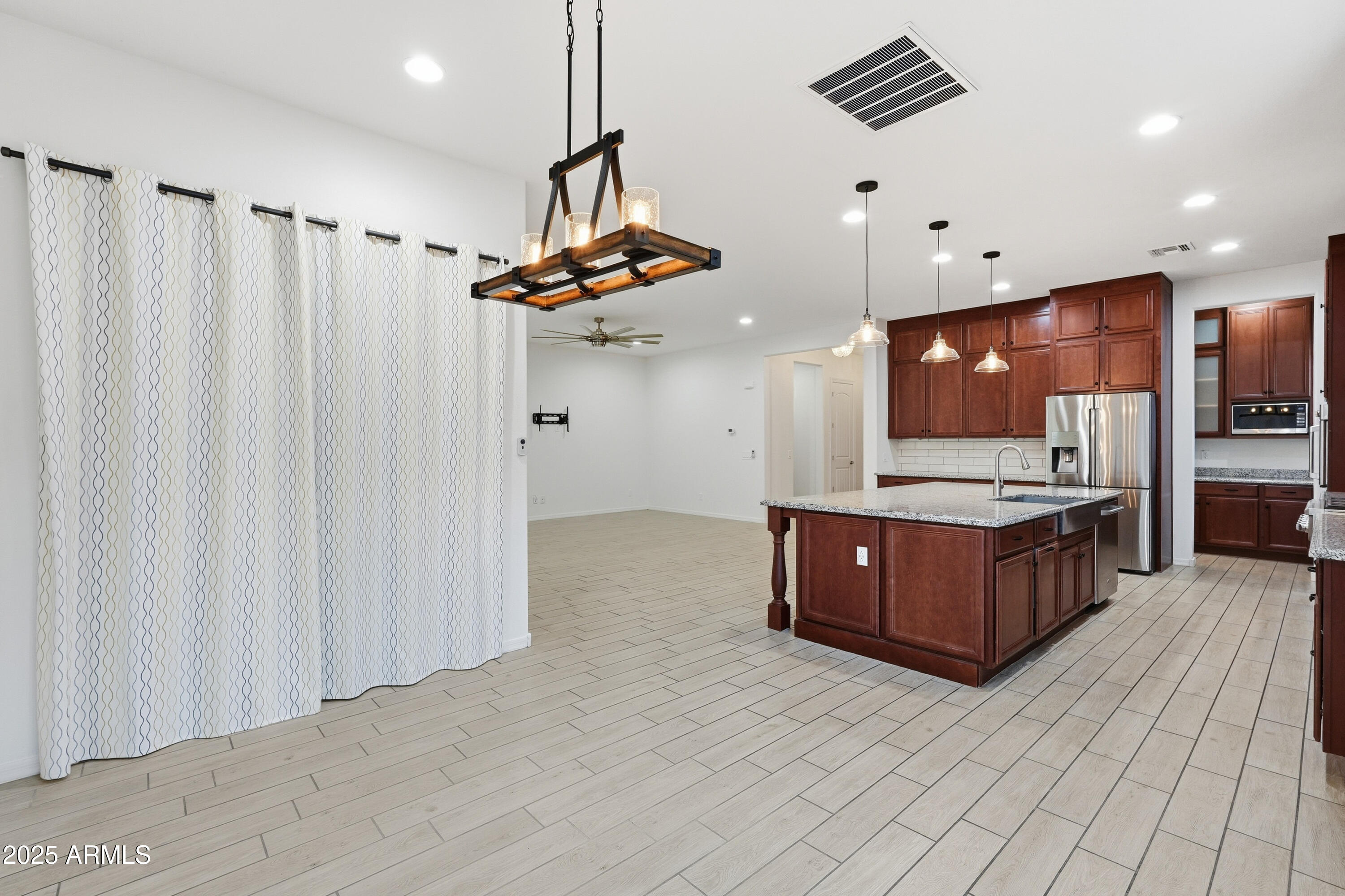 1432 East Pedro Road Phoenix, AZ 85042 - Photo 9 of 52 a large kitchen with stainless steel appliances a large counter top a stove a chimney a sink and living room view