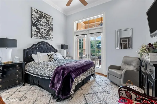 a bedroom with a bed couches chair and a flat tv screen on dresser