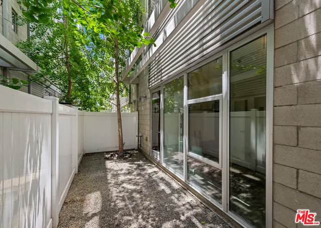 a view of a patio with couches table and chairs with wooden floor and fence